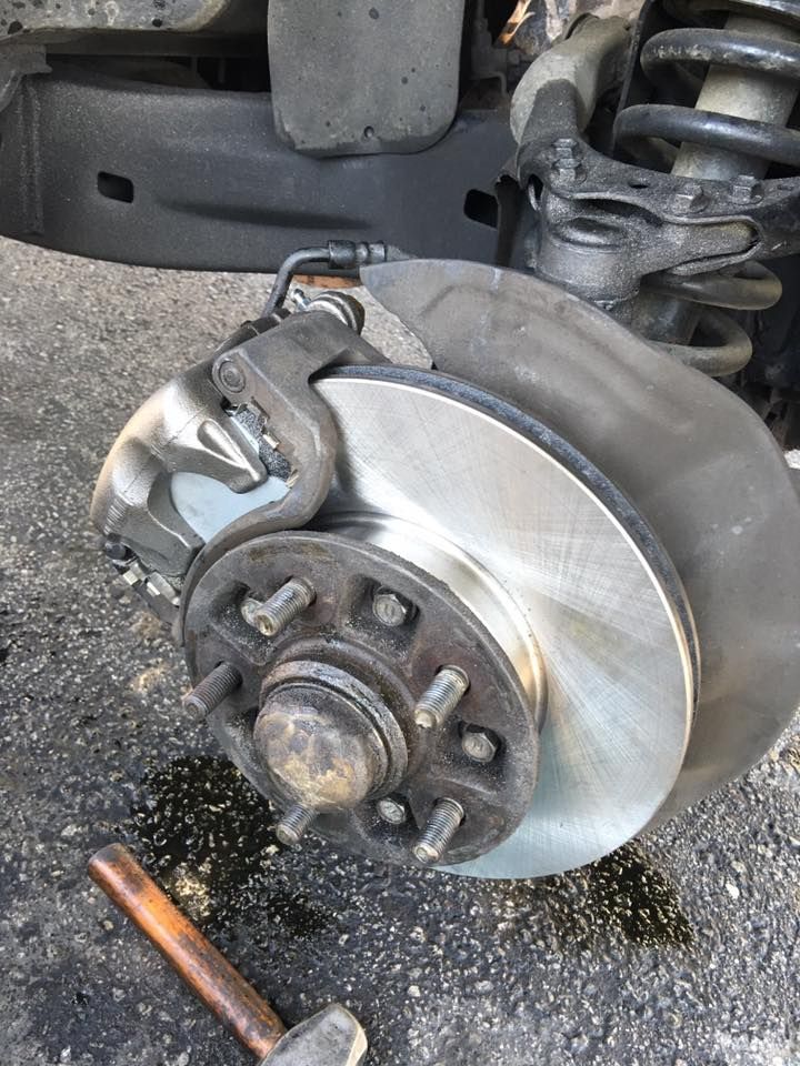 Car brake system, rotor and caliper, undergoing repair. New rotor installed.