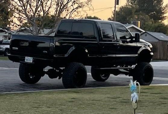 Black lifted pickup truck parked on grass, daytime.