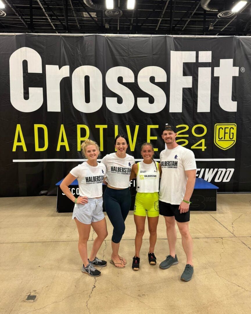 A group of people are posing for a picture in front of a crossfit sign.