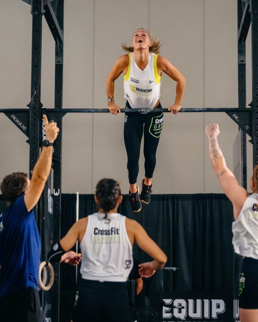 A woman is doing a pull up on a bar in a gym