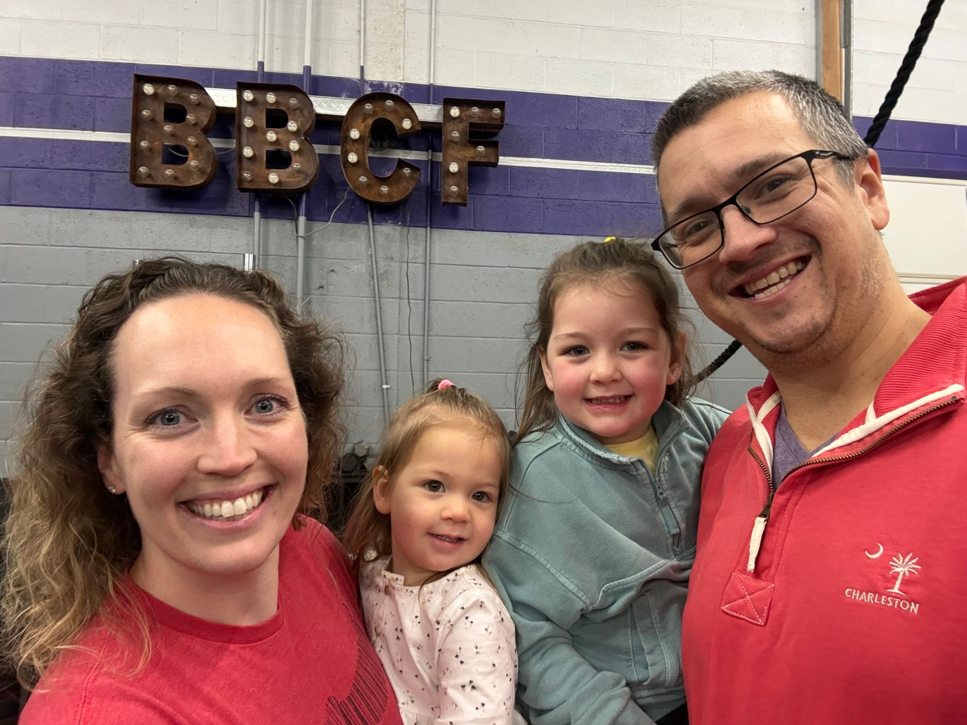 A family are posing for a picture in a gym.