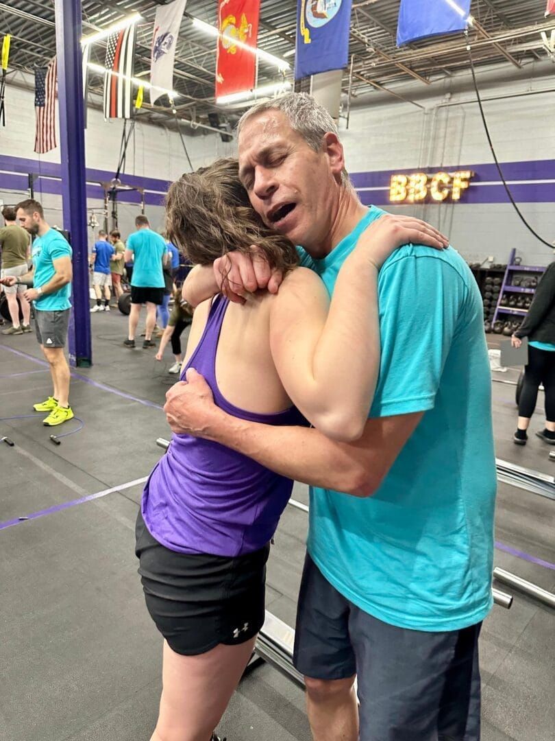 A man in a blue shirt is hugging a woman in a gym.