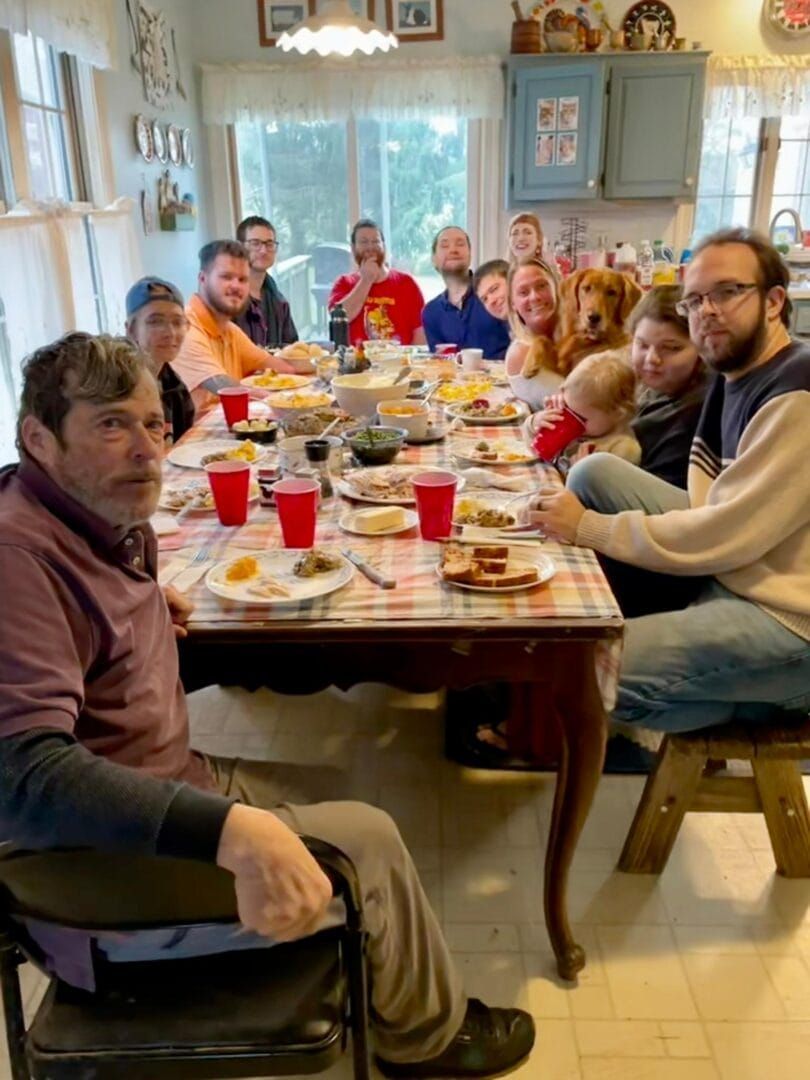 A group of people are sitting around a long table eating food.