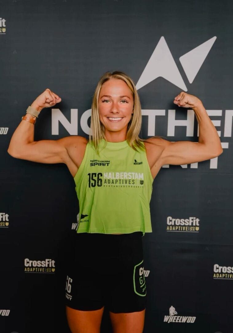 A woman is flexing her muscles in front of a sign that says north