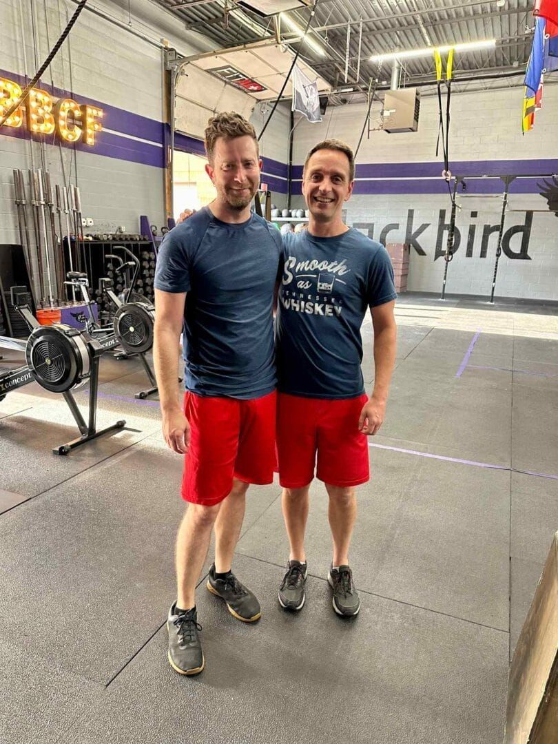 Two men are standing next to each other in a gym.