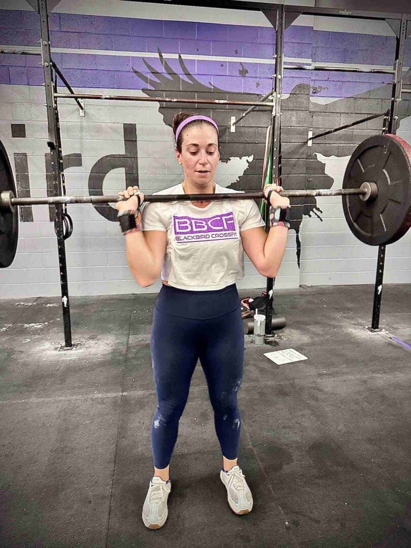 A woman is lifting a barbell in a gym.