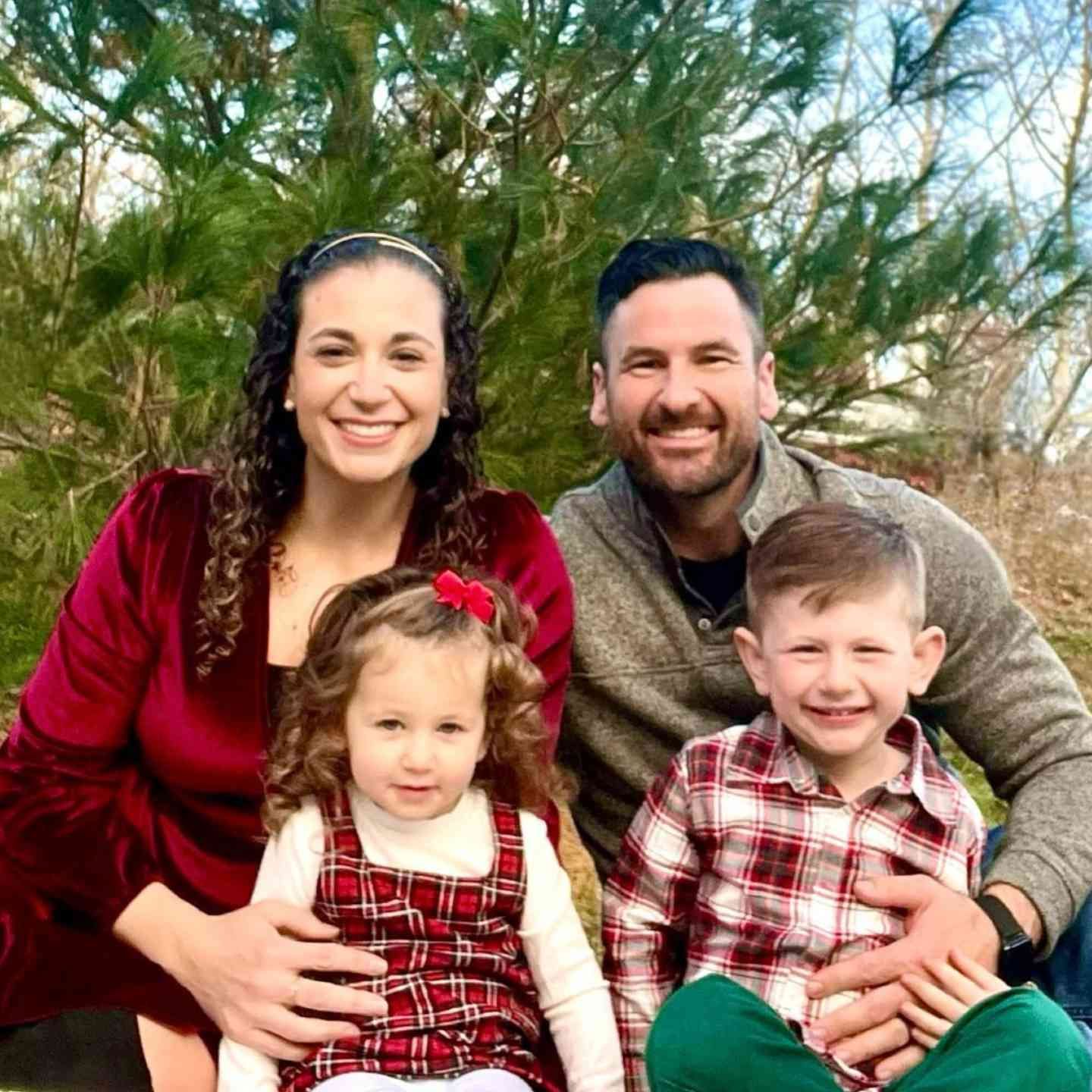 A family is posing for a picture in front of a christmas tree.