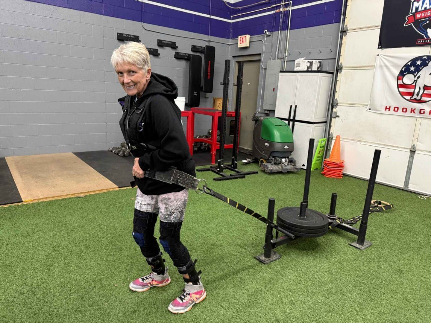 A woman is pulling a sled in a gym.