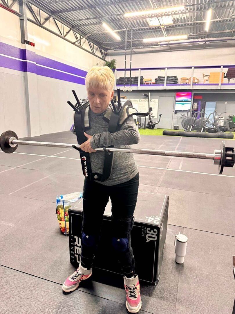 A young boy is lifting a barbell in a gym.