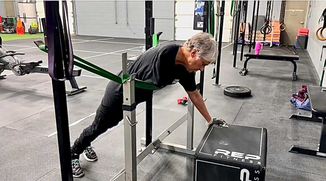 A man is doing push ups with a resistance band in a gym.