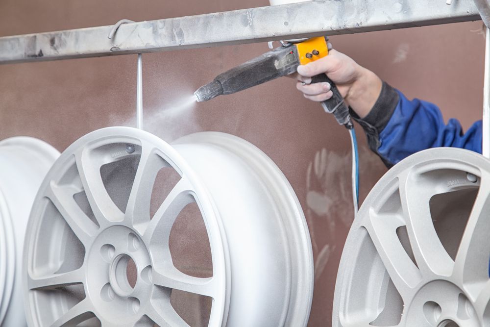 A Person is Spraying Powder Paint on a Set of Wheels — Sure Shot Sprayer Australia in Alice Springs, NT