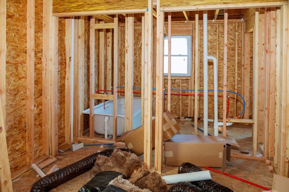 Bathroom under construction with exposed wooden studs, insulation, and plumbing.