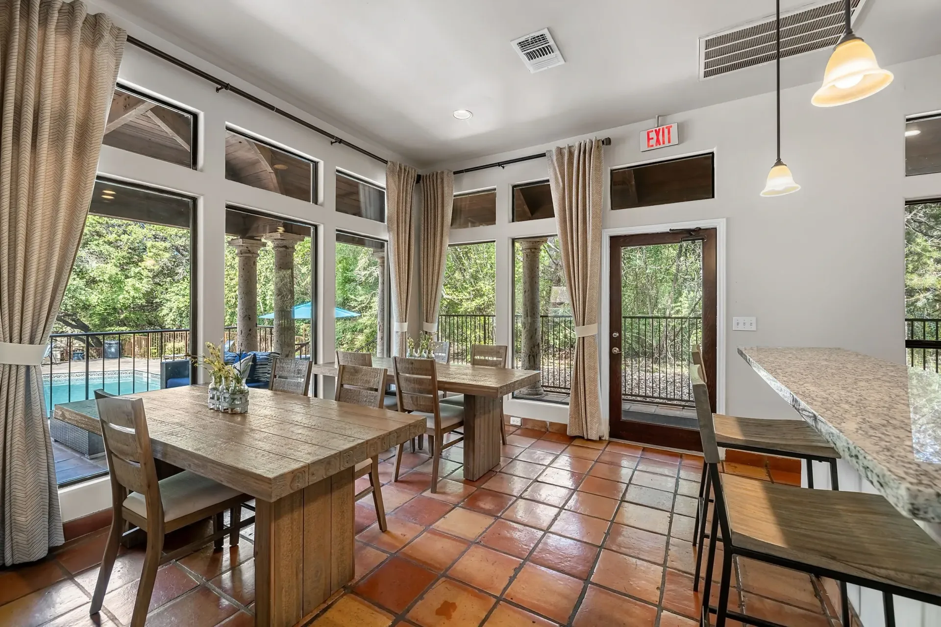 Dining area with tables and chairs overlooking a pool.