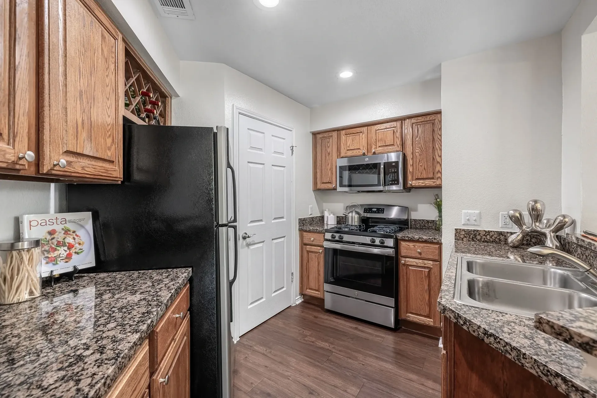 Kitchen with wood cabinets, granite countertops, stainless steel appliances, and a double sink.