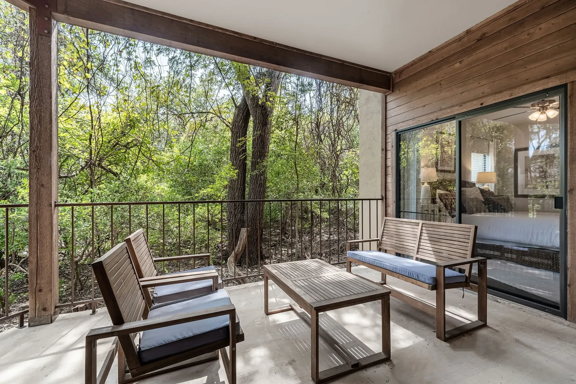 Balcony with seating and a view of trees.