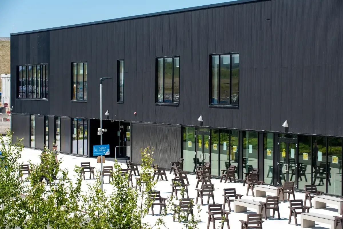 A man in a green jacket is standing in a gym.