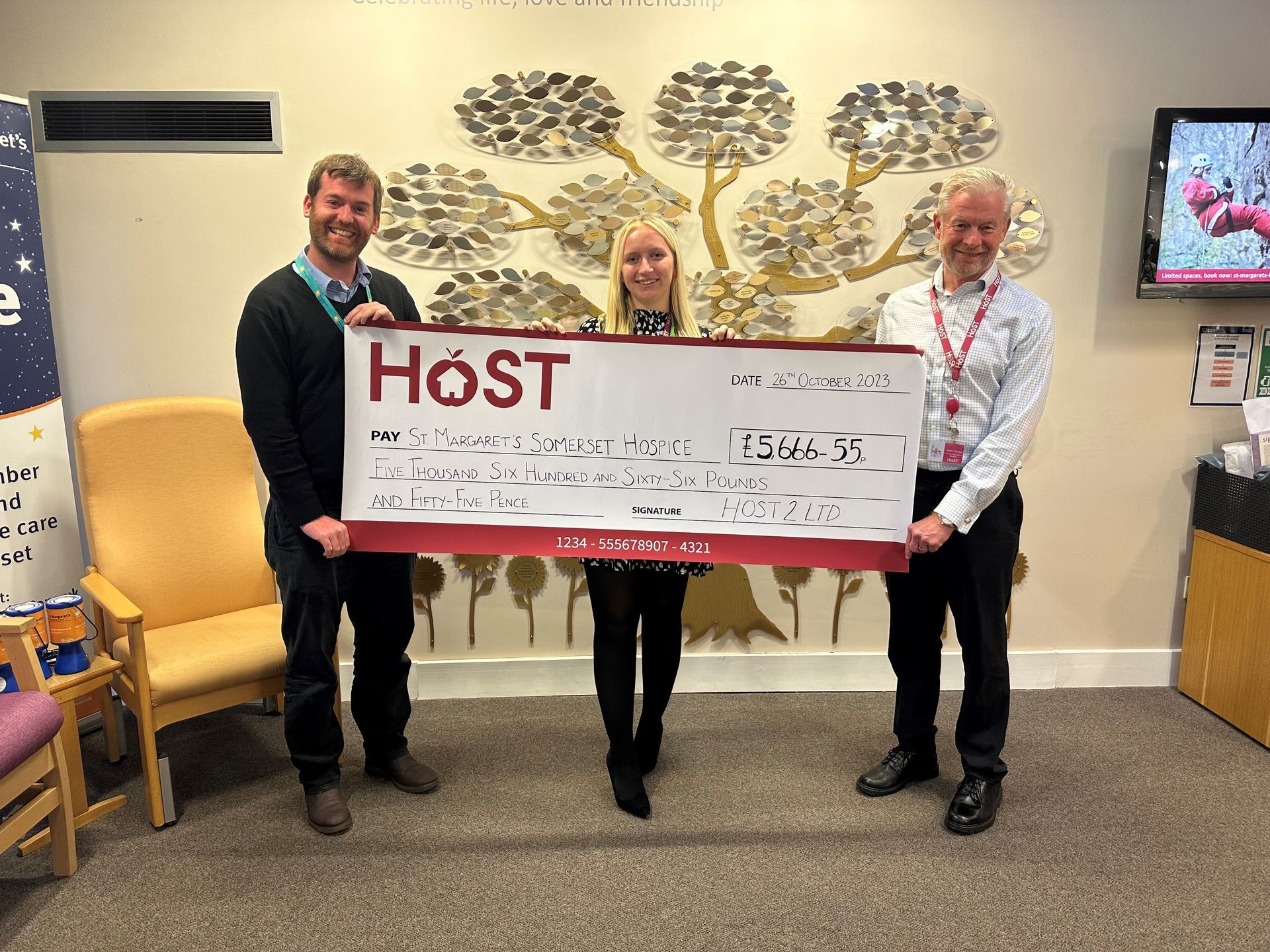 three people holding a check that says host on it