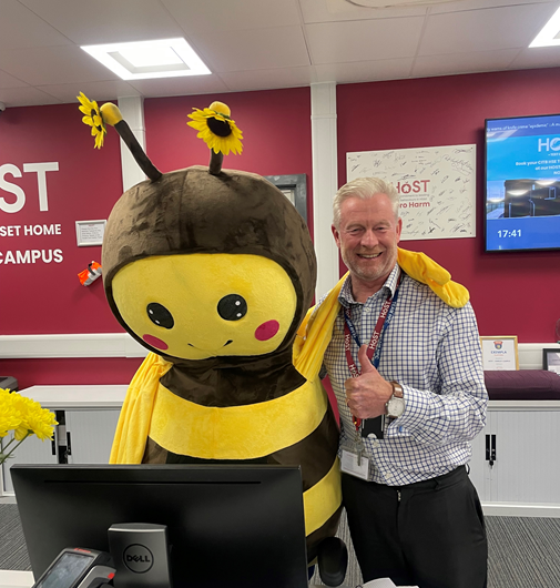 a man in a bee costume stands next to a dell computer