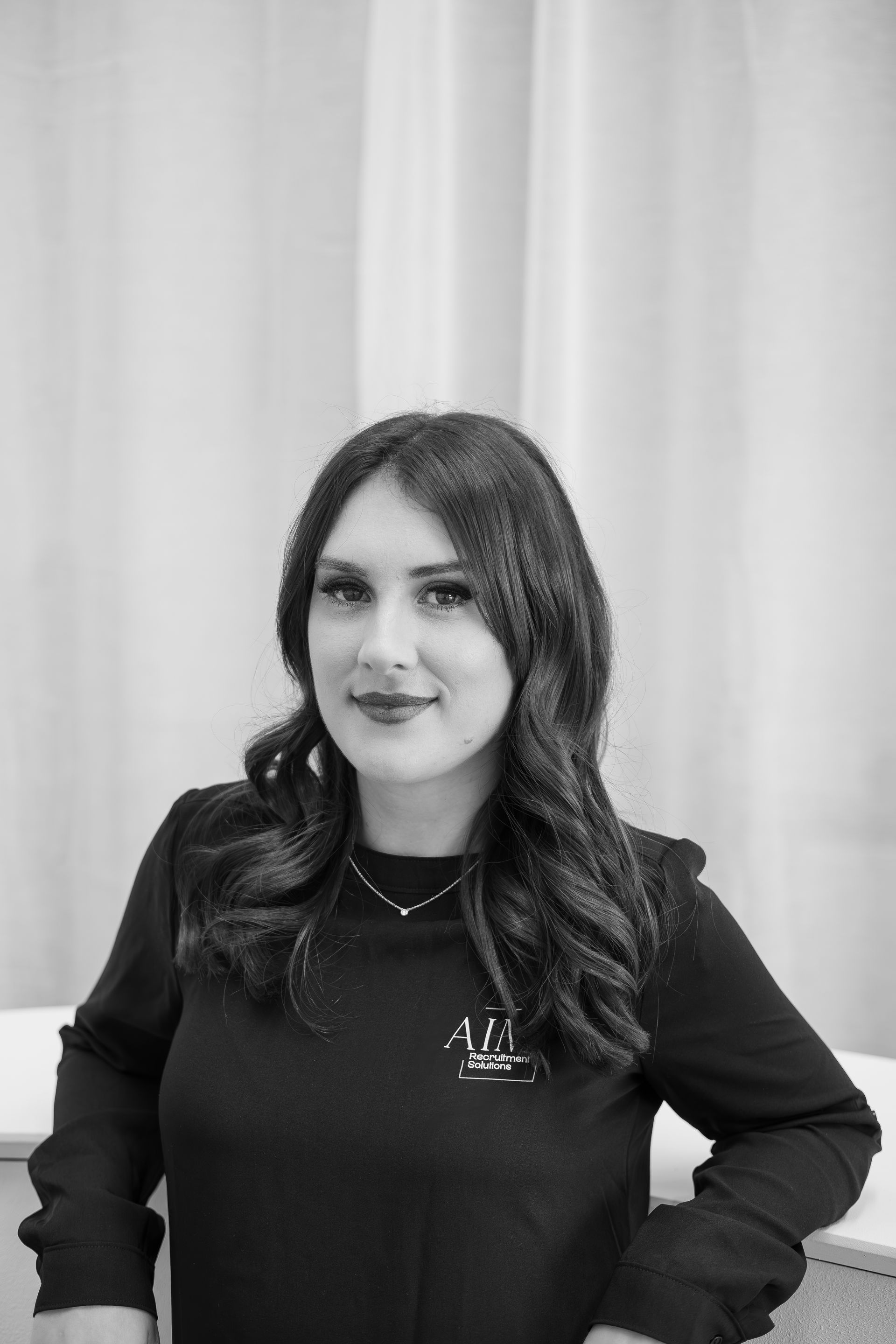 Two women writing on whiteboard in office, one smiling.