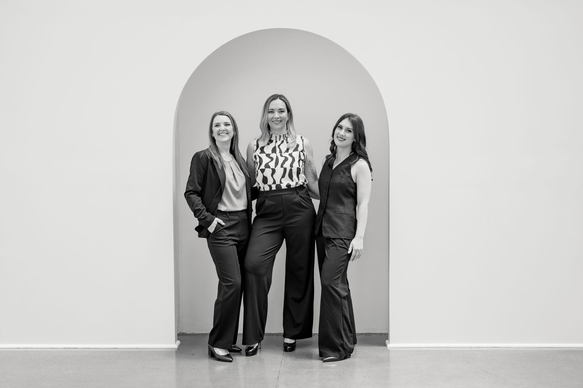 Two women writing on whiteboard in office, one smiling.
