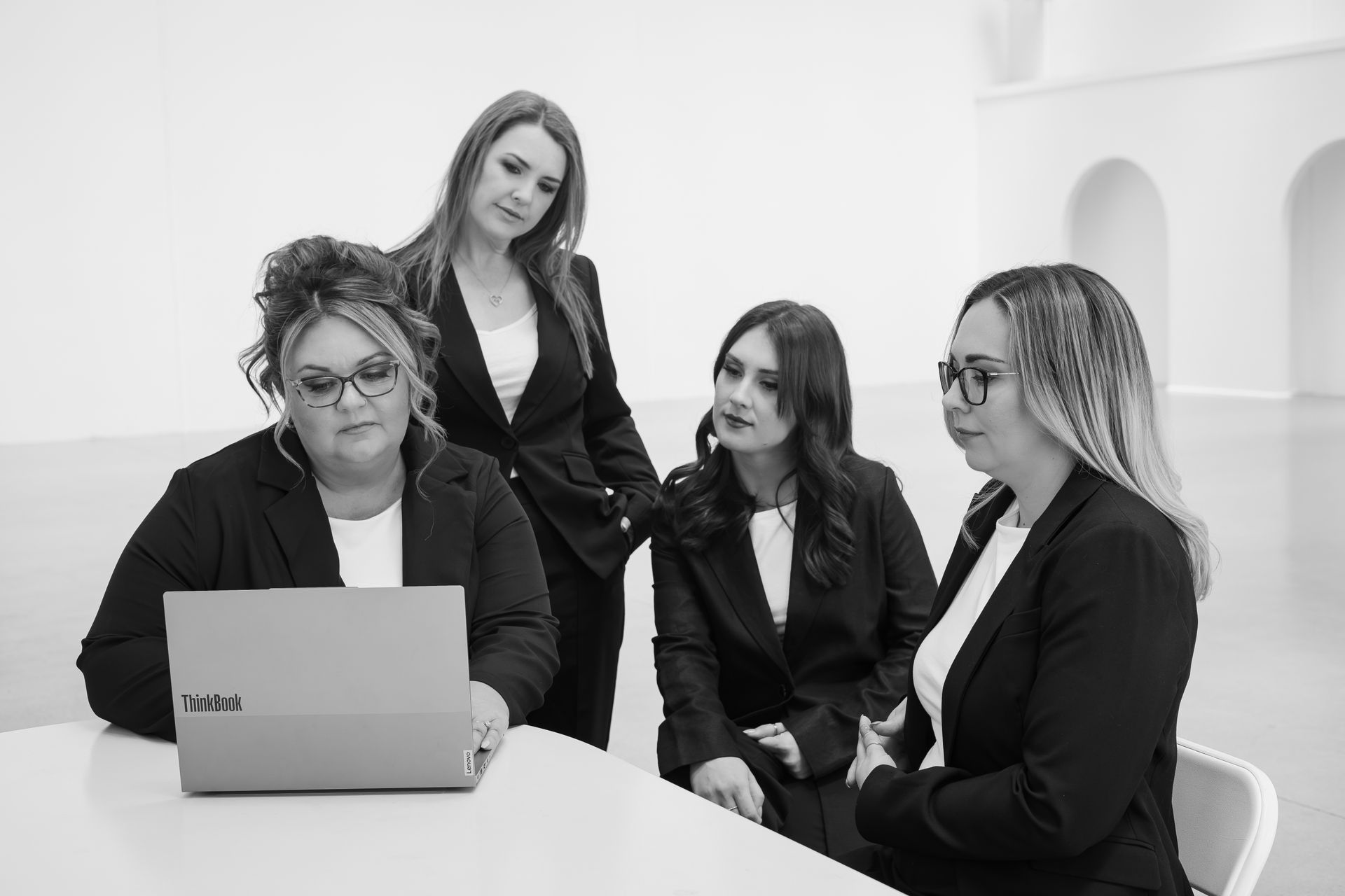 Two men shake hands over a table in an office setting.