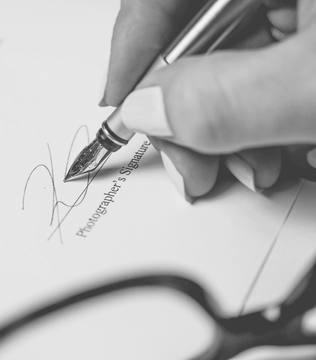 Two people seated, facing each other at small table with laptops, near large window.