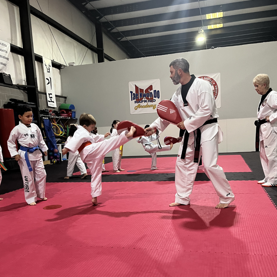 Master Dustin Sands coaching a child through a kicking drill at Tennessee Taekwondo in Mt. Juliet