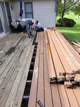 A Man Is Working On A Wooden Deck In Front Of A House - Owingsville, KY - Withrow Builders
