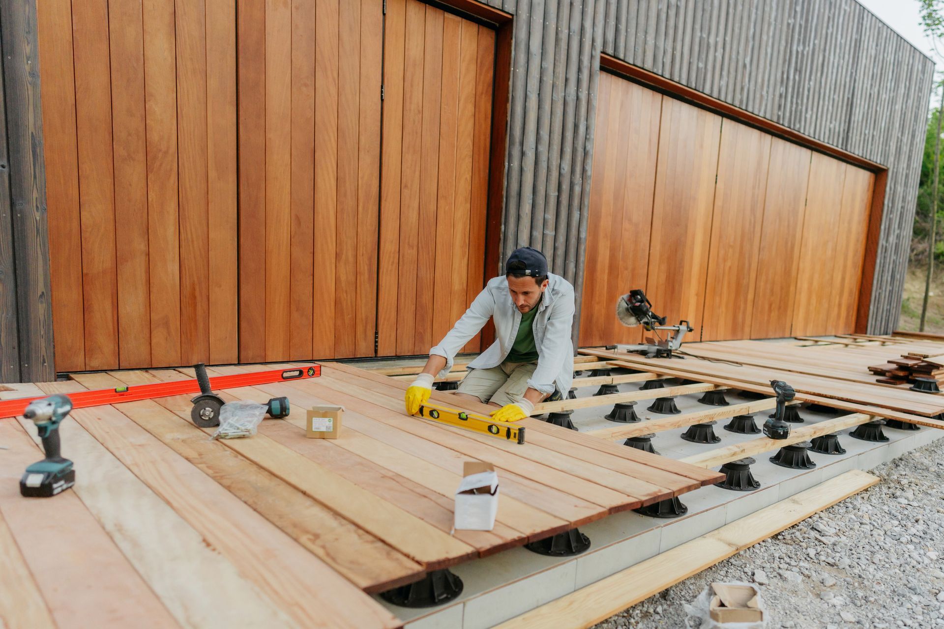 A Man Is Laying A Wooden Deck In Front Of A Garage Door - Owingsville, KY - Withrow Builders