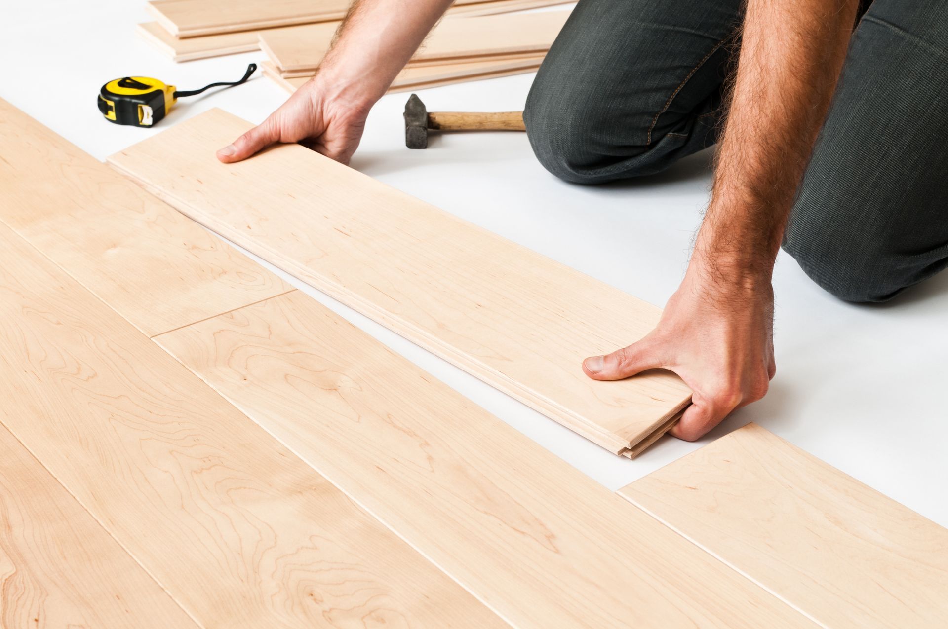 A Man Is Kneeling Down To Install A Wooden Floor - Owingsville, KY - Withrow Builders