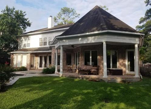 A large house with a porch and a large lawn in front of it.