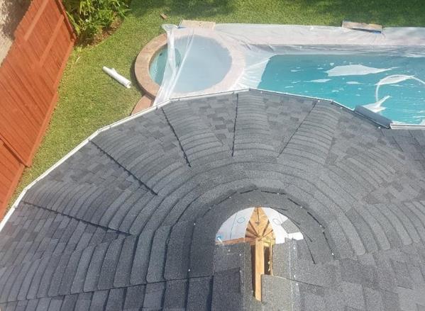An aerial view of a roof with a pool in the background.