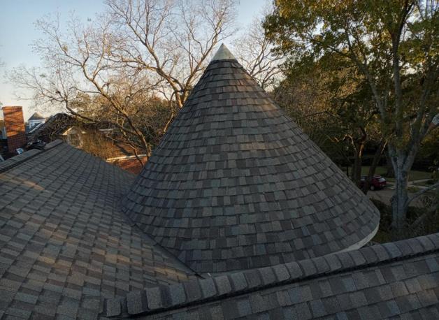 A roof with a cone shaped roof and trees in the background.