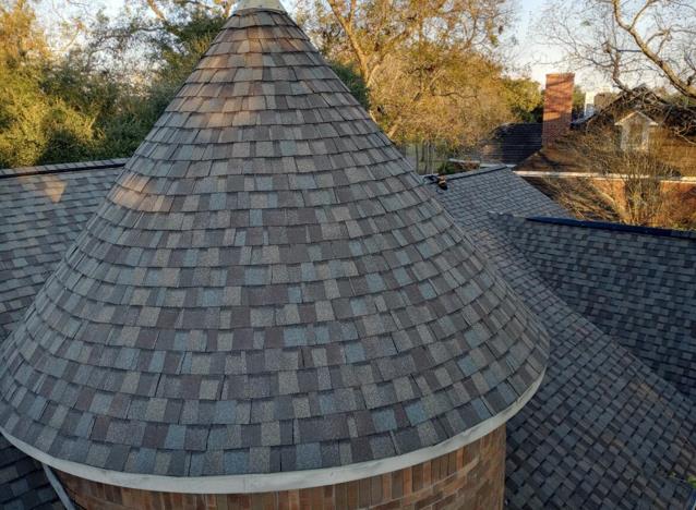 The roof of a house with a cone shaped roof and a chimney.