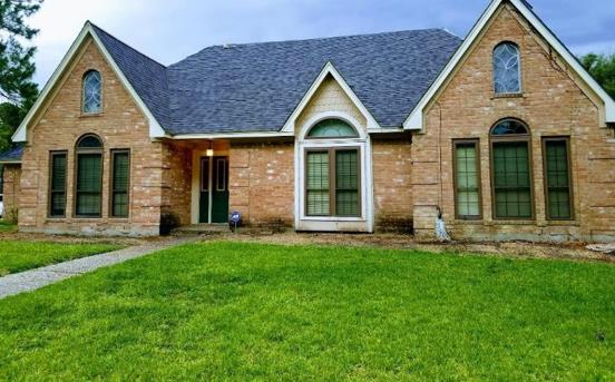 A large brick house with a blue roof and green windows