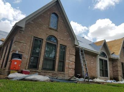 A brick house with a ladder in front of it is being remodeled.