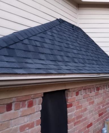 A brick building with a black roof and white siding
