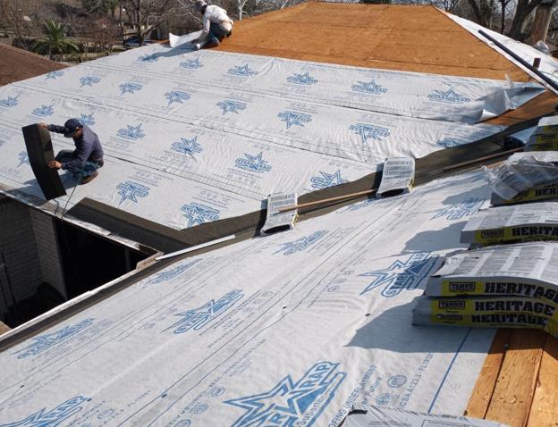 A man is working on a roof with heritage roofing paper