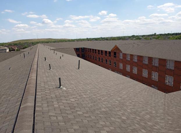 A large brick building with a roof that has shingles on it