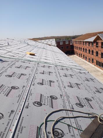A large roof with a lot of shingles on it and a brick building in the background.