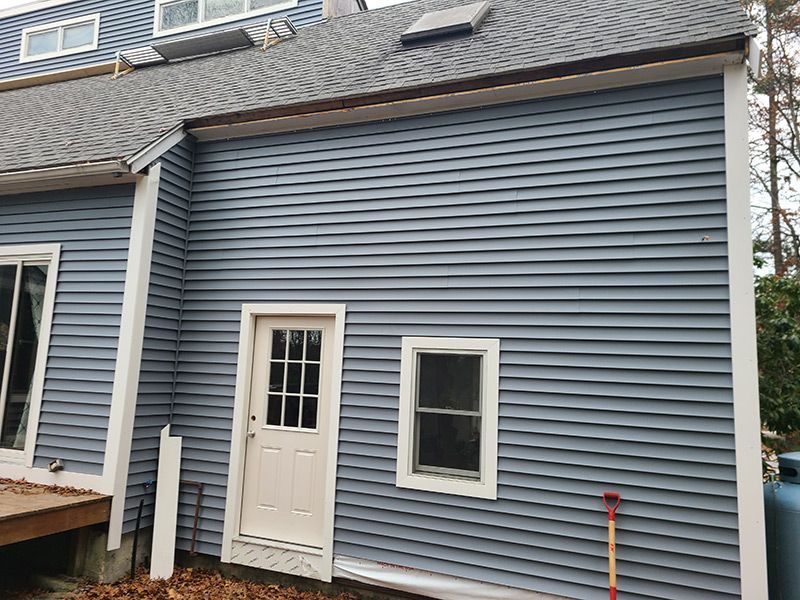 Side of a house with blue siding, white trim, door, and windows.