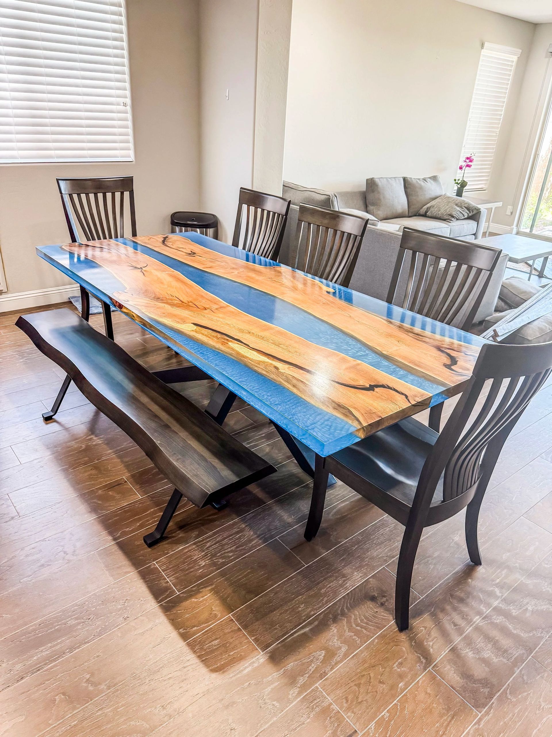 Dining room with a wooden table, blue resin, chairs, and bench.