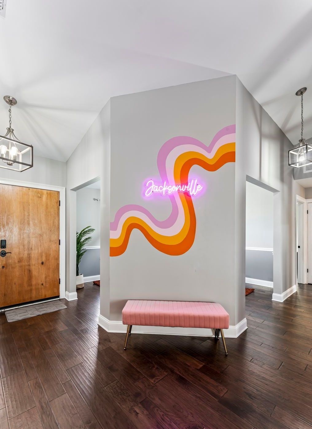 Funky Flowing lines with pinks yellow and orange. Hand painted accent wall in Jacksonville airbnb/short term rental with neon light that says 