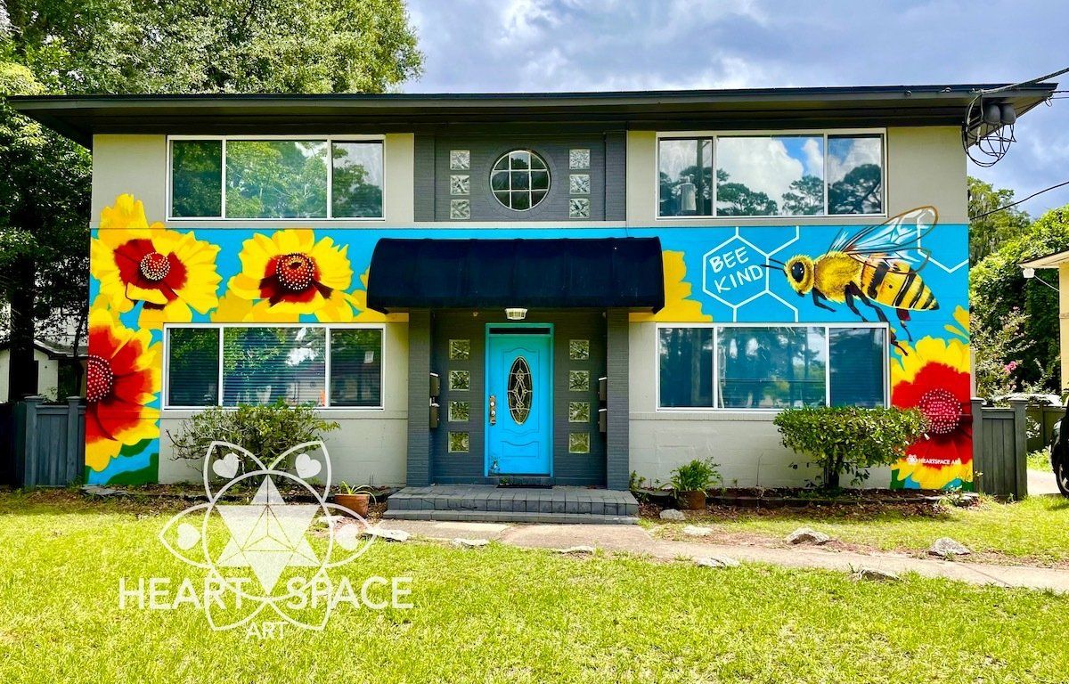 Bee Kind spray paint mural at fourplex short term rental in Jacksonville, Florida featuring native Florida flowers and a cute fuzzy bee.