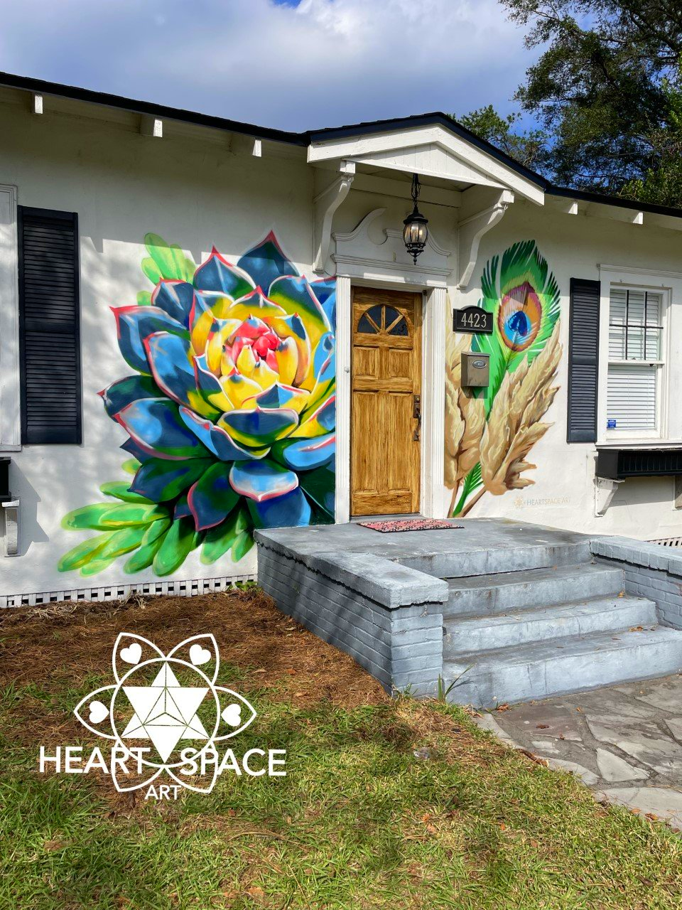 Spray-painted mural on a rental located in Avondale. The left side shows a vibrant succulent and on the right a peacock feather and wheat plant.