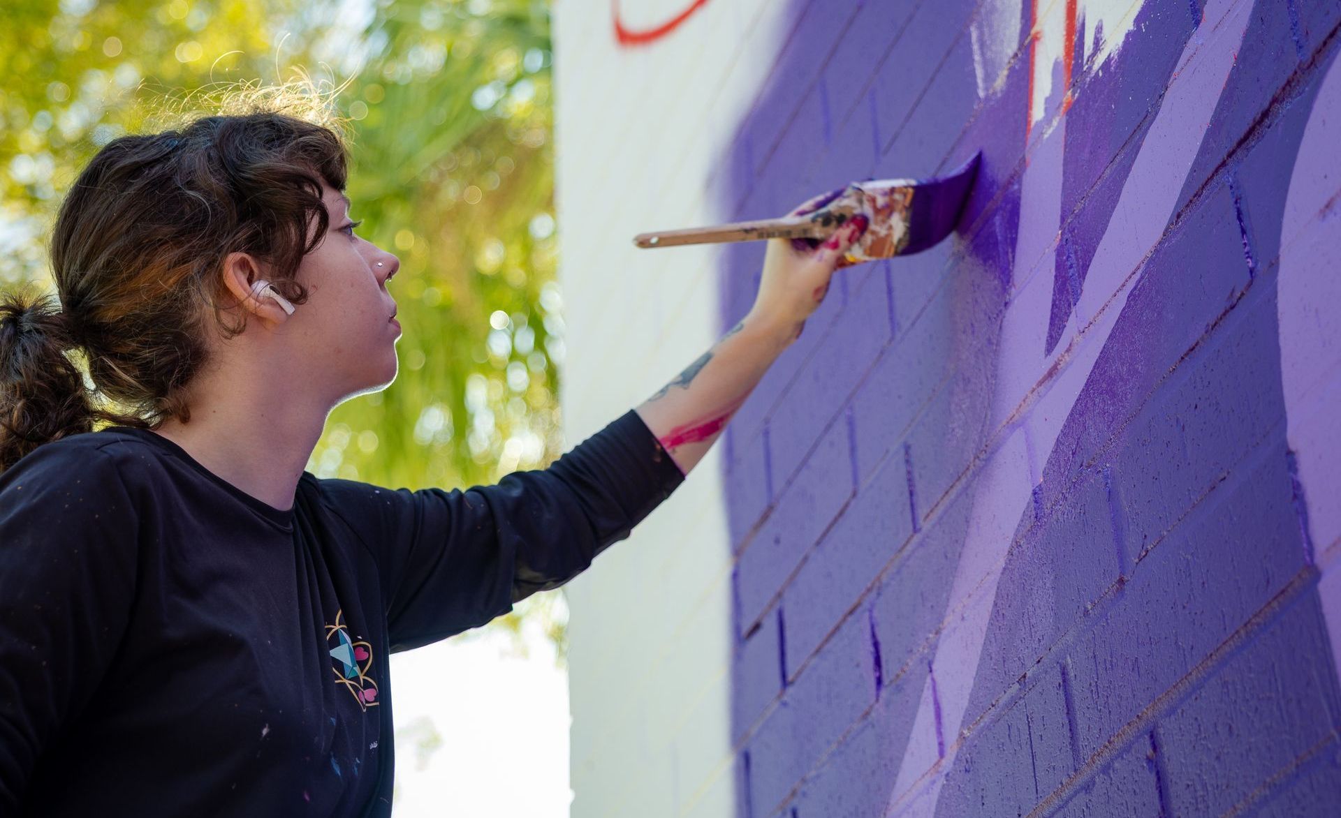 Angie Pulak painting a mural on the corner of State and Main St. in Downtown Jacksonville. This mural was commissioned by Gateway Jax.