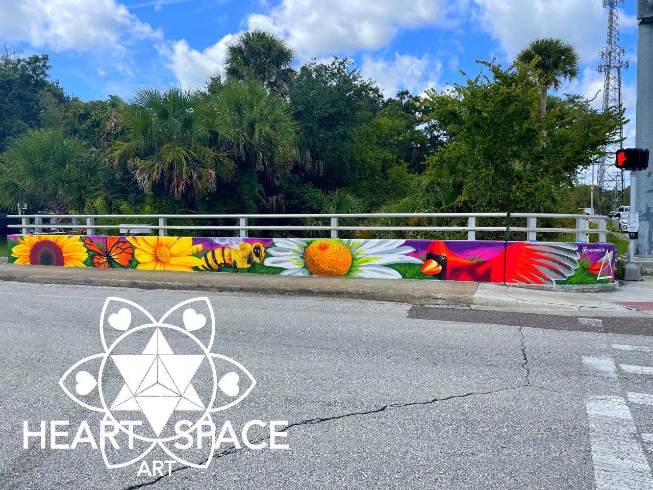 Spray Painted Mural on sidewalk wall located in Holly Hill Florida. Featuring sunflower, daisy, cardinal, bee, and butterfly.