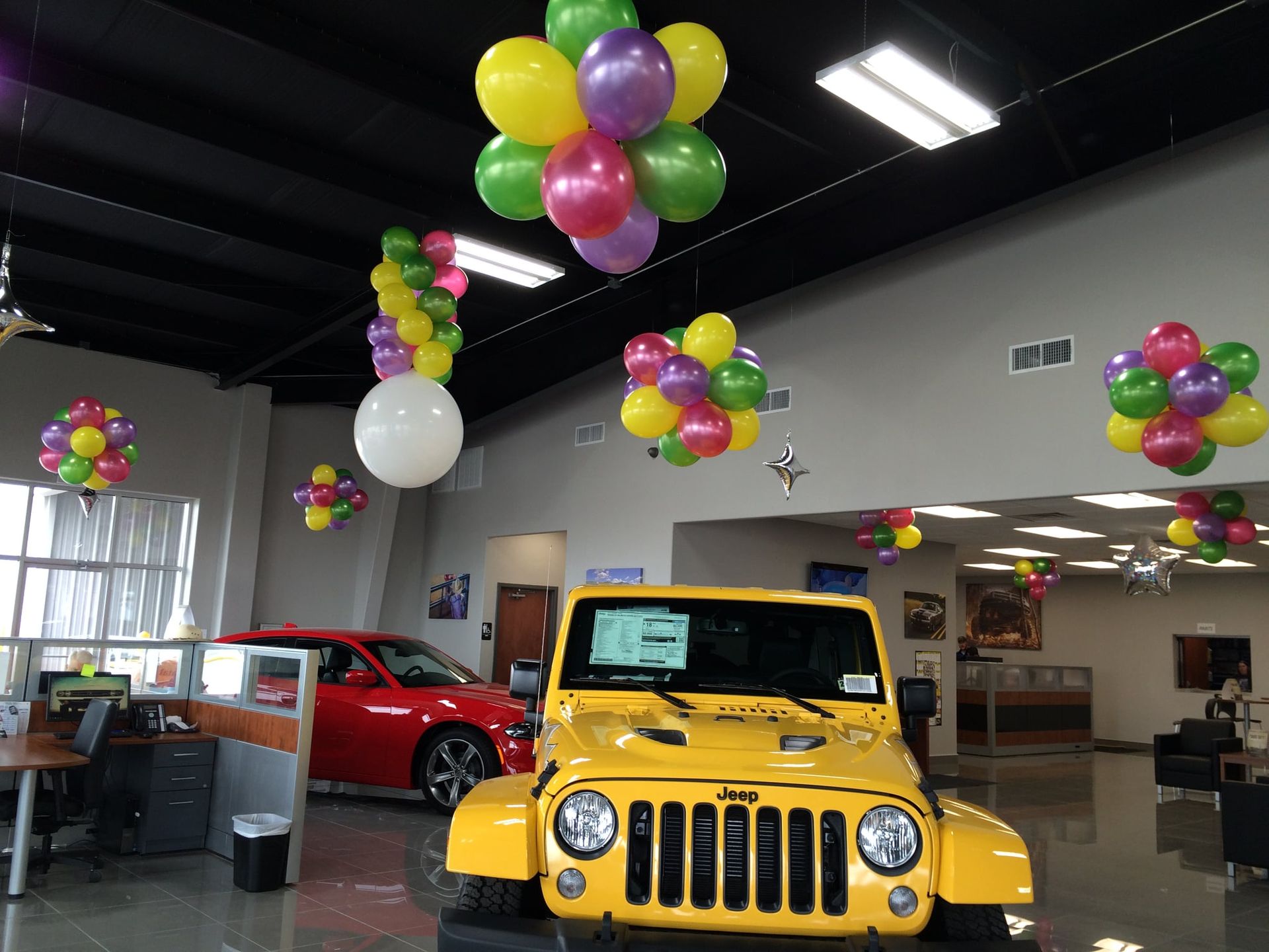 A yellow jeep with balloons hanging from the ceiling