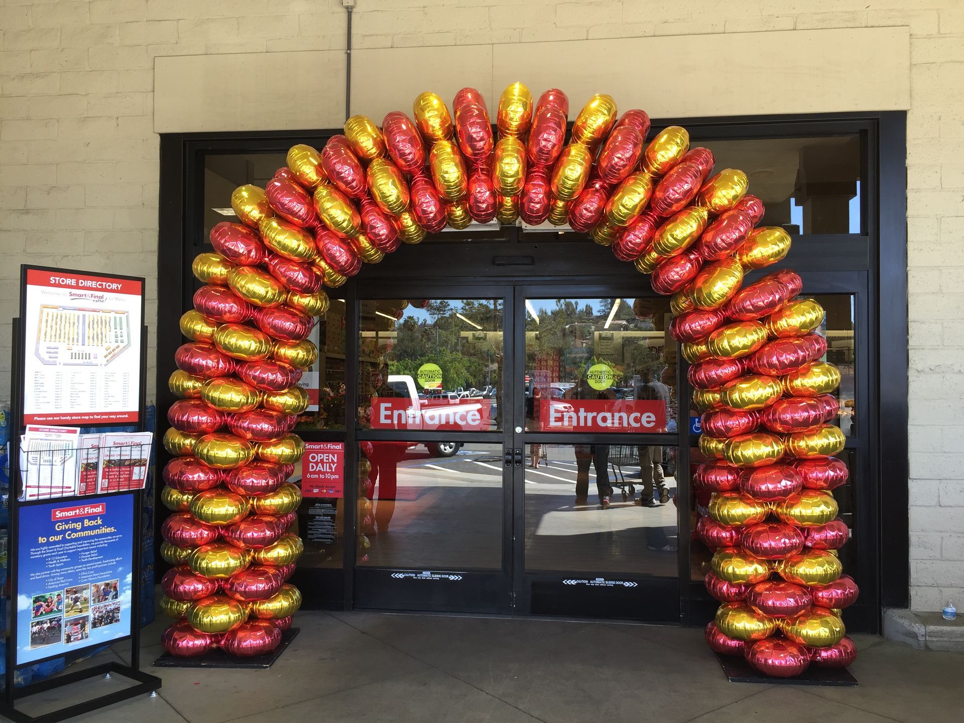 The entrance to a store is decorated with red and gold balloons.