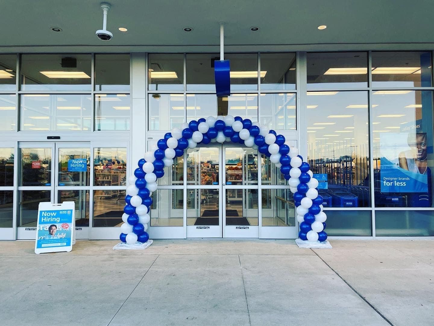 A blue and white balloon arch in front of a store